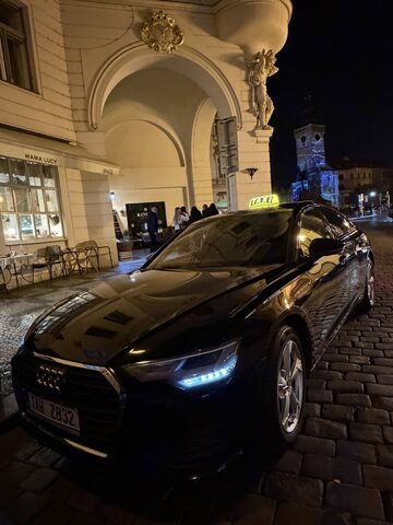 Černé Audi taxi v noční Praze u historické budovy
